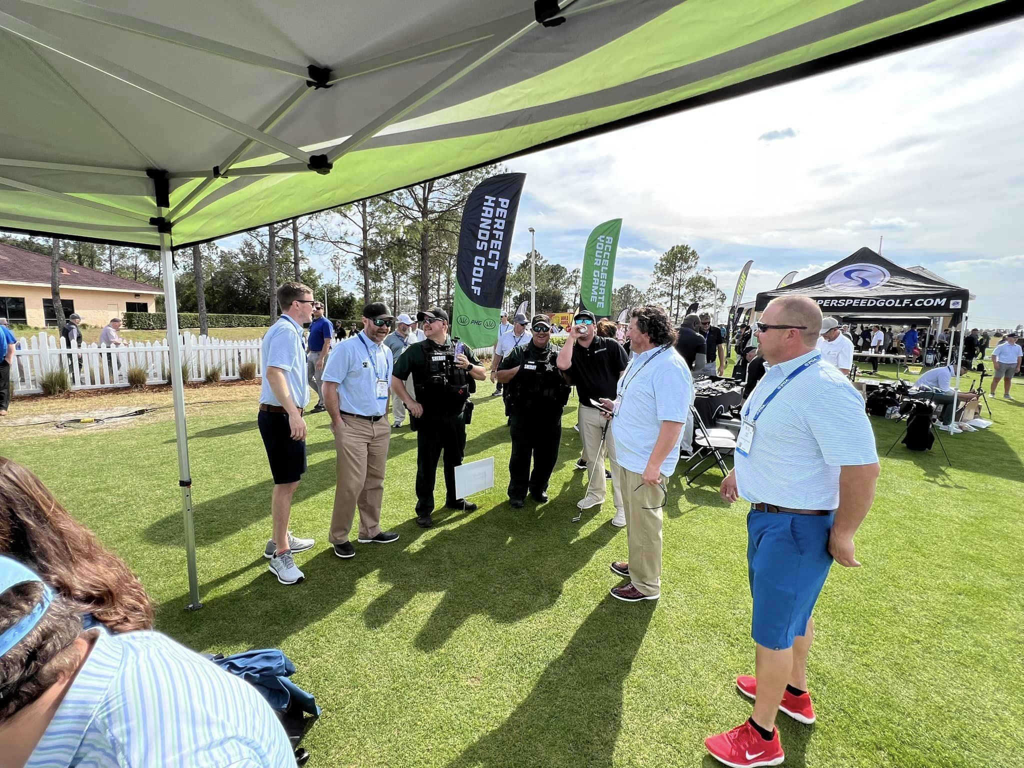 People conversing at an outdoor golf event with on an artificial turf installed by Turf and Sims.