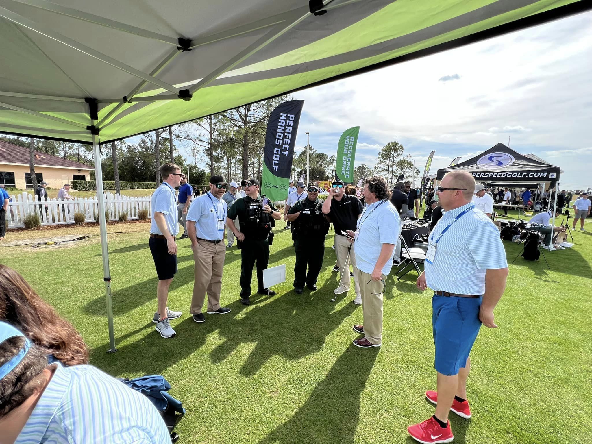 Home People conversing at an outdoor golf event with on an artificial turf installed by Turf and Sims.