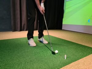 Golf player playing indoors on a golf simulator, closeup view of driving shot