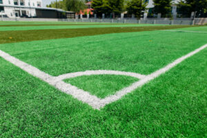 Vibrant green synthetic grass soccer field with clear white boundary lines, showcasing the modern standard for sports arenas.