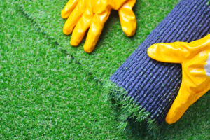 Close-up of a gloved hand of a worker expertly installing artificial lawn grass during the turf laying process.