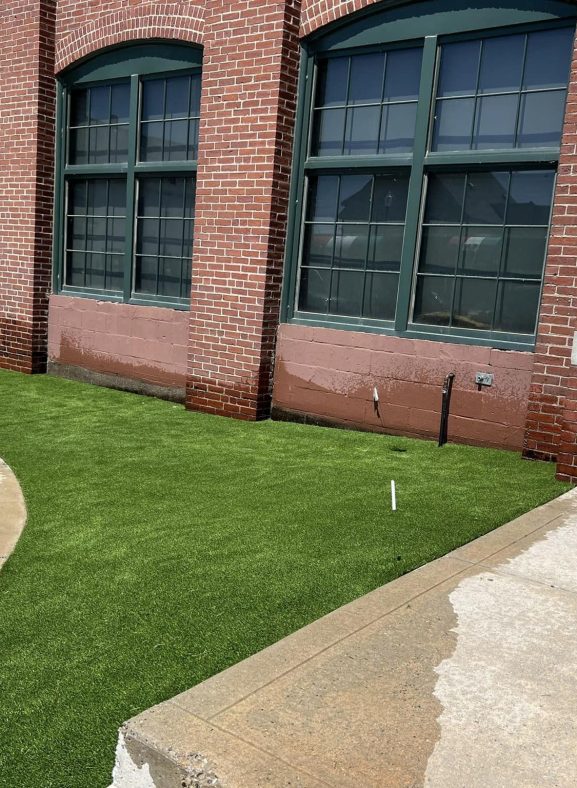 Vibrant artificial grass installed by St.Germain's, enhancing the outdoor space in front of a building in Massachusetts.